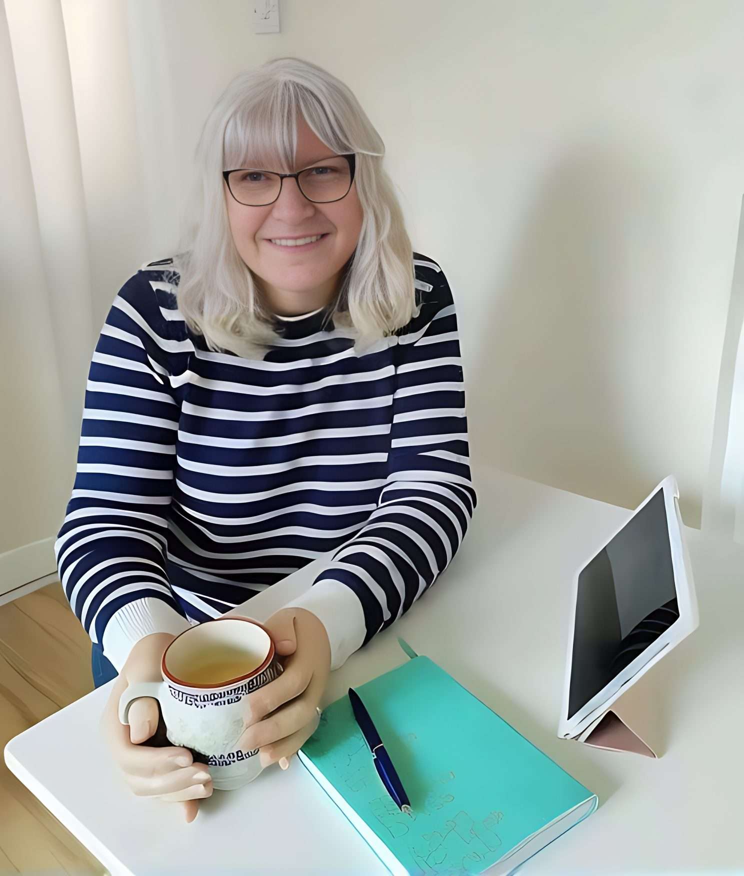 Joanna Kelsall sitting at table with coffee cup and journal